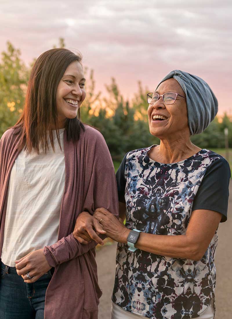 Adult woman and senior woman walking outside and smiling.