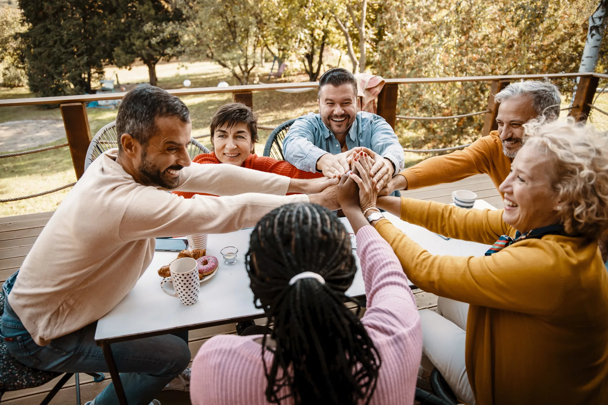 Group of adults sitting in a circle and reaching their hands into the middle.