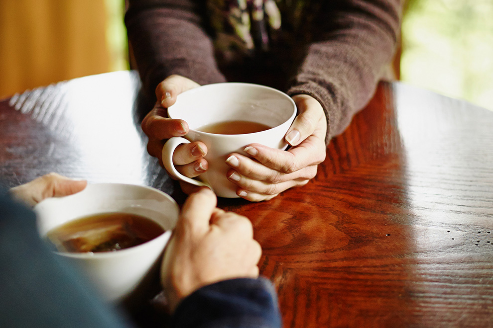 Two pairs of hands holding cups of tea.