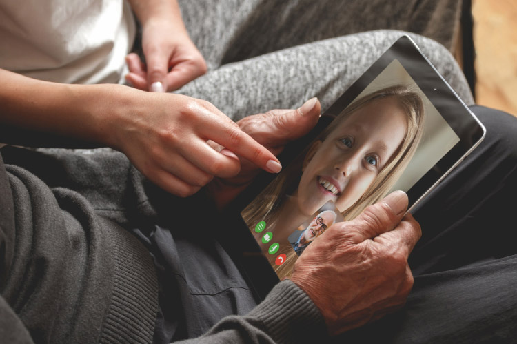 A Companion helping an older man with a video call to his granddaughter.