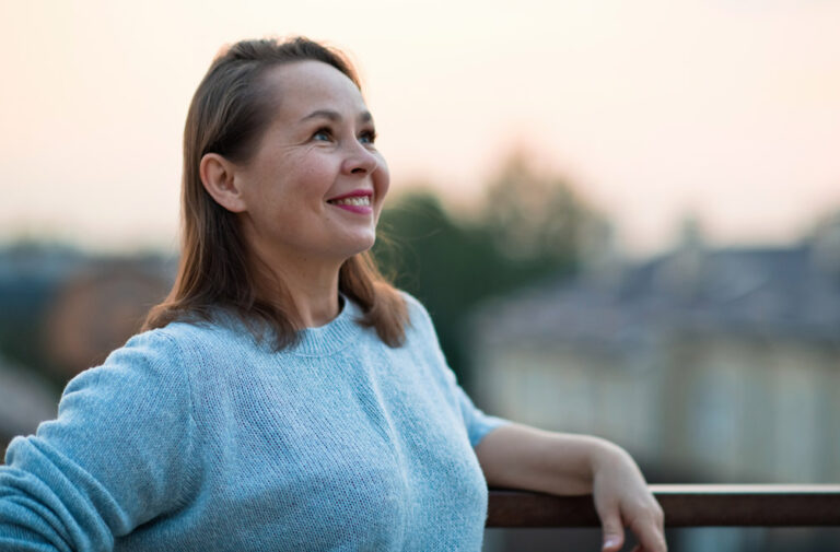 Woman smiling while standing outside.